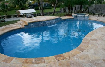 backyard swimming pool with waterfall and artistic pavers patio after renovation