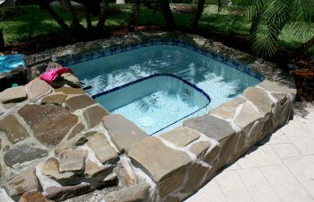 backyard in-ground jacuzzin with natural stone finishing