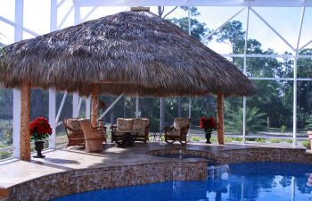 garden indoor swimming pool with a tiki hut and comfortable seats on a pool patio