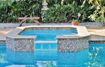 backyard swimming pool with jacuzzi and pool deck after renovation