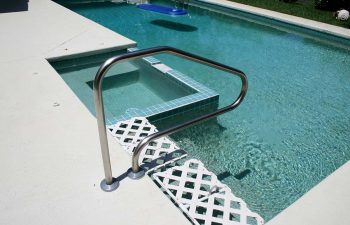 backyard in-ground swimming pool with jacuzzi and paver deck after renovation