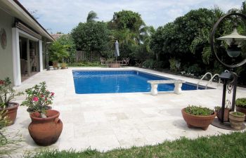 classic swimming pool with paver patio and garden furniture in a landscaped backyard