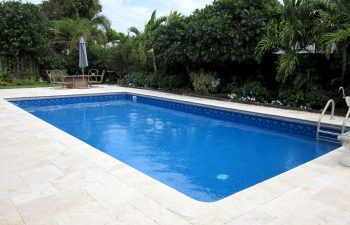 classic swimming pool with paver patio and garden furniture in a landscaped backyard