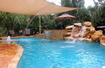 backyard swimming pool with jacuzzi and built-in hardscape waterfall