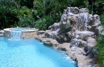 outdoor spa pools with a hardscape waterfall on the pool edge