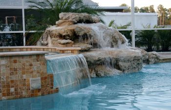 outdoor spa pools with a hardscape waterfall on the pool edge