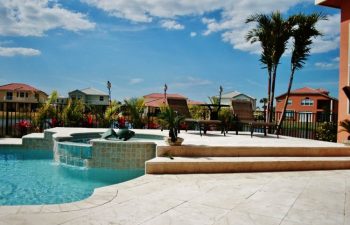 artistic pavers patio with sunbeds by a backyard swimming pool