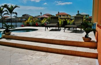 artistic pavers patio with sunbeds by a backyard swimming pool