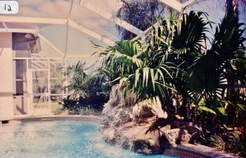 glass enclosed swimming pool with a hardscape waterfall