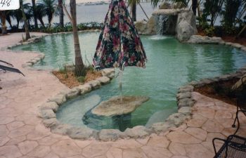 backyard swimming pool with a hardscape waterfall and flagstone patio