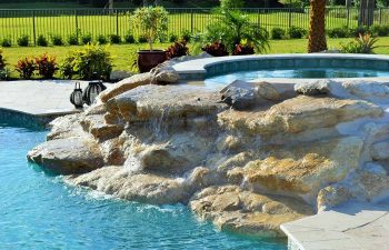 backyard spa pools with a hardscape waterfall formed between jacuzzi and pool