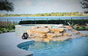 backyard spa pools with a hardscape waterfall formed between jacuzzi and pool