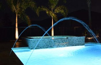 night view of a bakyard swimming pool with fountains