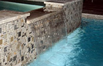 backyard spa pool with a waterfall and decorative tiles