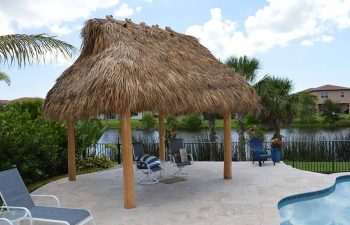 tiki hut with sunbeds on a backyard swimming pool patio