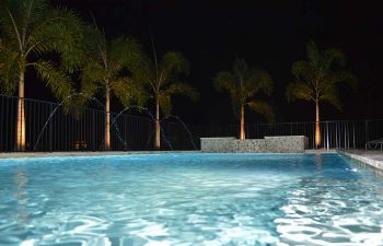 night view of a bakyard swimming pool with fountains