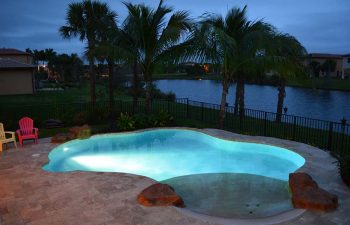 night view of a backyard beach entry swimming pool