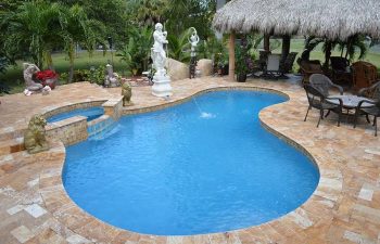 backyard swimming pool with Travertine deck and outdoor furniture under tiki roof and