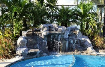 glass enclosed spa pool with hardscape waterfall and built-in fointains