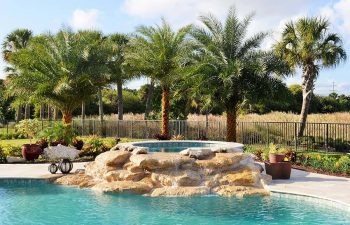 backyard spa pools with a hardscape waterfall formed between jacuzzi and pool