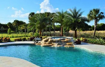 backyard spa pools with a hardscape waterfall formed between jacuzzi and pool