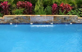 backyard pool waterfall coming out a stone brick wall