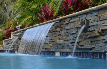 backyard pool waterfall coming out a stone brick wall