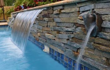 backyard pool waterfall coming out a stone brick wall