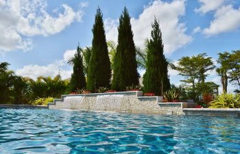 swimming pool with a waterfall in a landscaped backyard