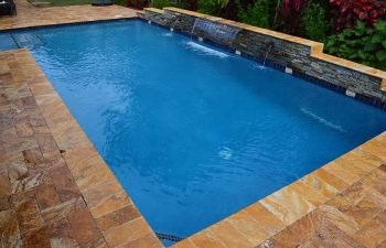 backyard swimming pool with a waterfall and Travertine paver deck