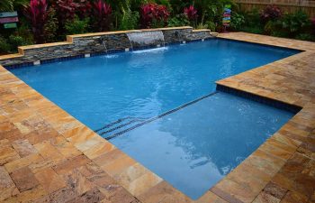 backyard swimming pool with a waterfall and Travertine paver deck