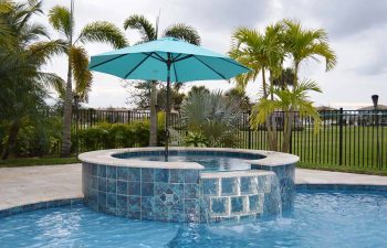 backyard swimming pool and jacuzzi with a waterfall