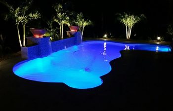 night view of a backyard swimming pool and outdoor lighting