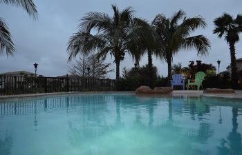 backyard swimming pool and plastic garden chairs on a pool patio