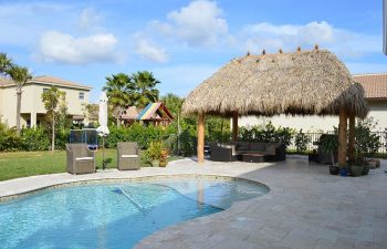 Tiki hut and outdoor furniture on a backyard pool deck