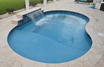 indoor swimming pool with a waterfall with a view of the backyard
