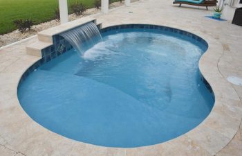 indoor swimming pool with a waterfall with a view of the backyard