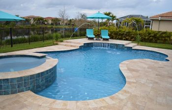 backyard swimming pool with water features and sunbeds on a deck