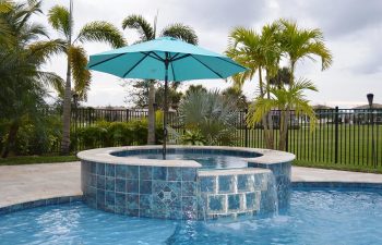 blue sun umbrella over a jacuzzi and backyard swimming pool