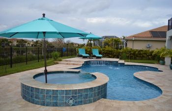 backyard swimming pool with water features and Travertine deck