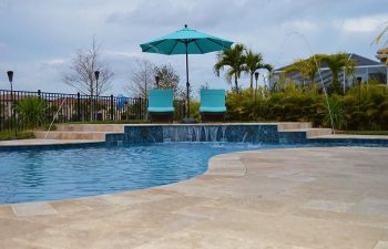 backyard swimming pool with waterfall Travertine paver patio