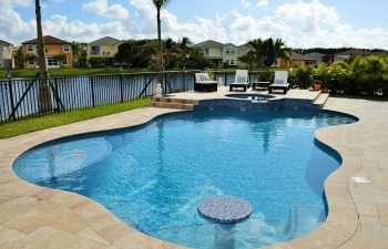 backyard swimming pool with light blue water color and paver deck