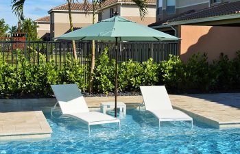 two sunbeds under umbrella placed in a swimming pool basin