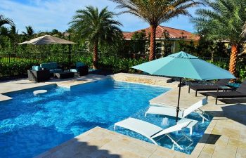 modern backyard swimming pool with sunbeds and outdoor furniture on a deck