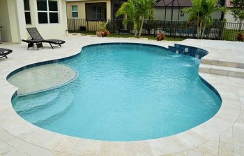 backyard swimming pool with water features and Travertine deck