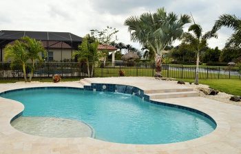 backyard swimming pool with water features and Travertine deck