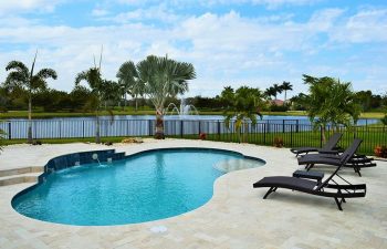 backyard swimming pool with water features and Travertine deck