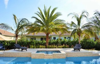 sunbeds by a backyard swimming pool with jacuzzi and waterfall