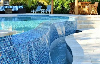 outdoor swimming pool with decorative blue tiles and waterfall