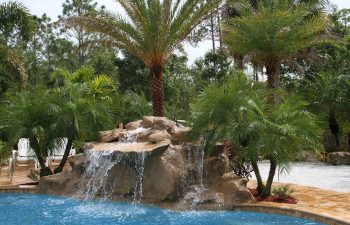 outdoor spa zone with a hardscape waterfall on the edge of the swimming pool